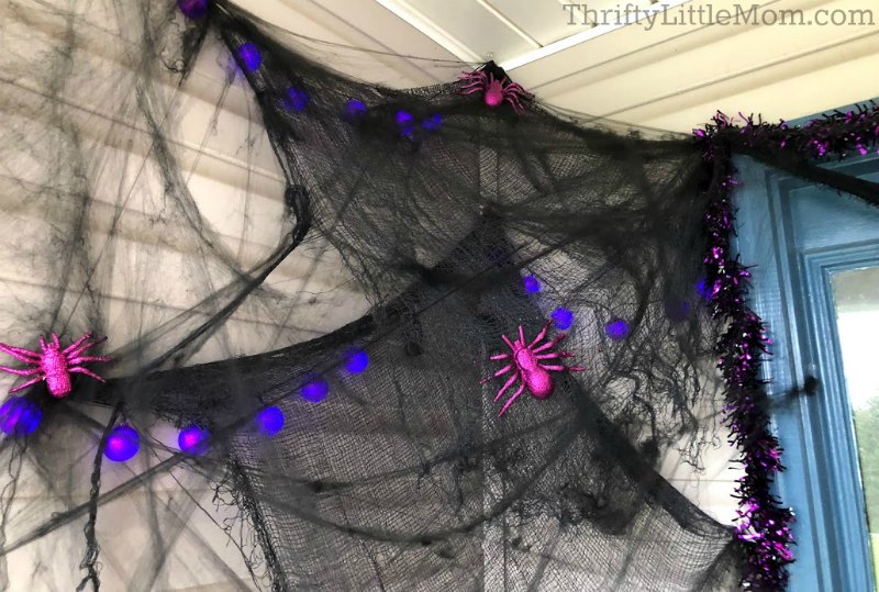 black spider web Halloween prop outside with purple spiders