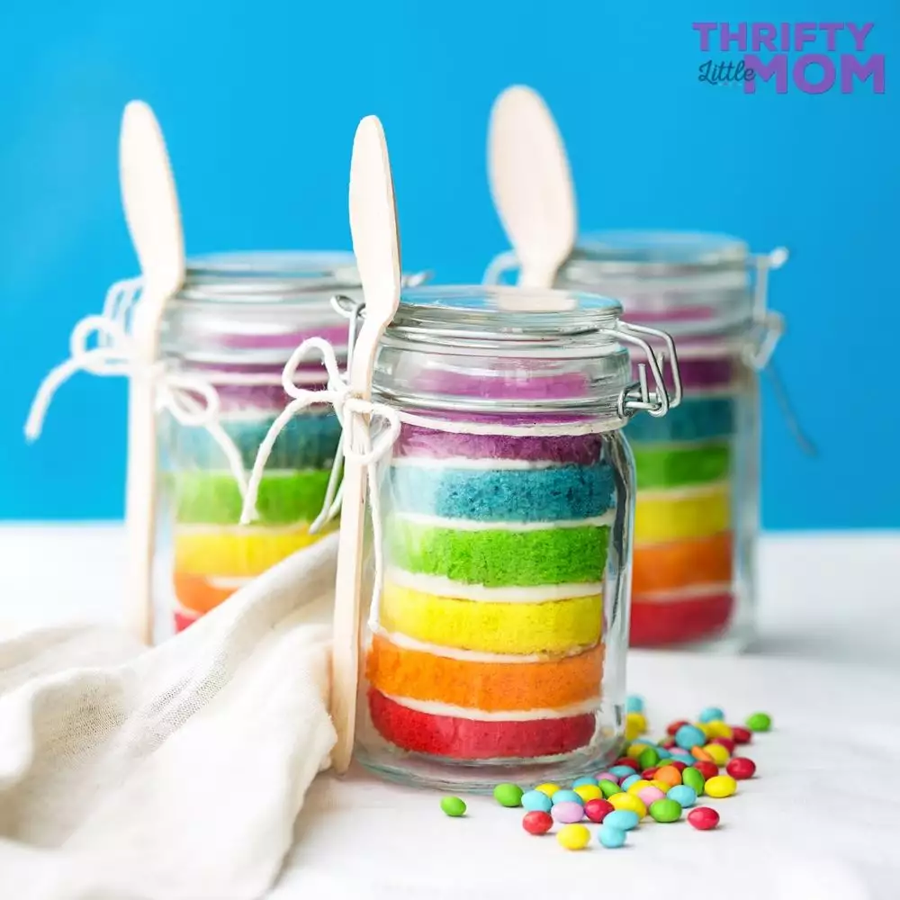 layers of rainbow cake in jar with spoon